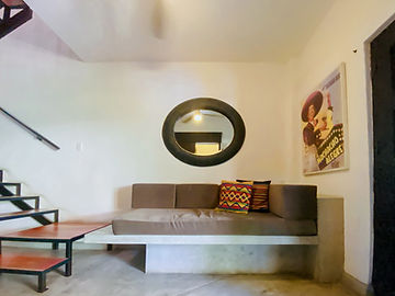 Sala de loft con sofá, espejo redondo y cuadros